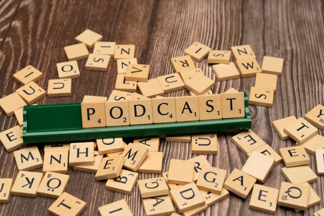 Wooden letter tiles on a board spelling the word 'Podcast', symbolizing digital media and creativity. Podcast SEO attribution methods compared and explained