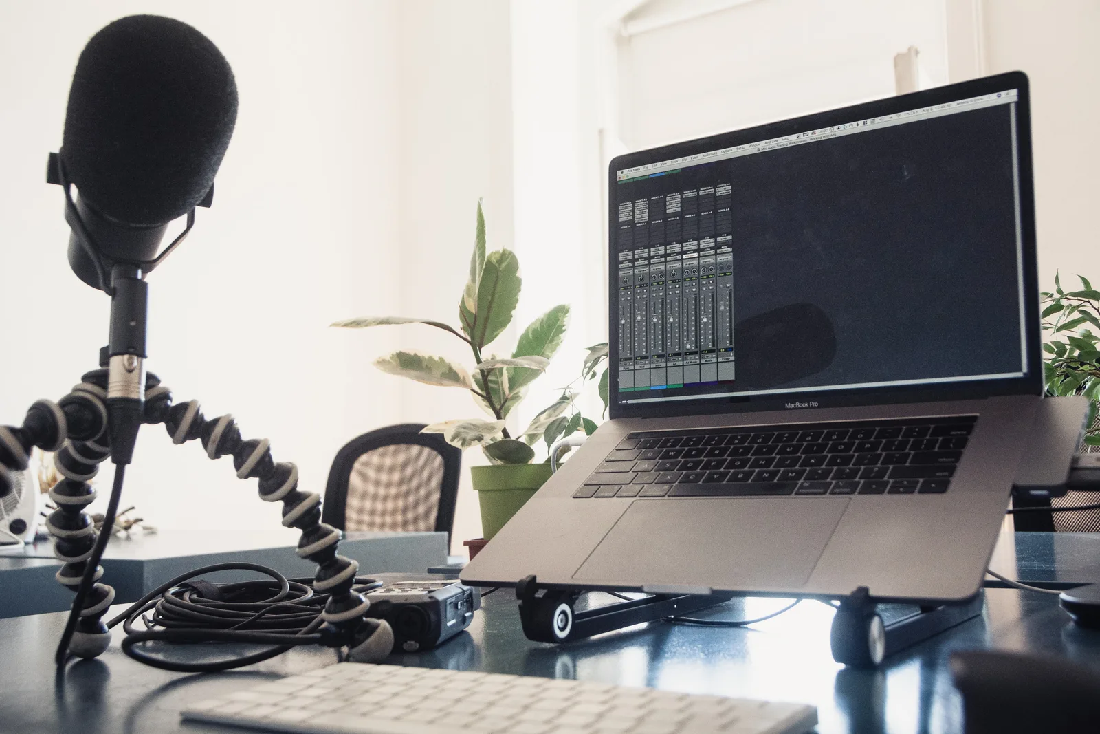 A detailed studio setup featuring a laptop and microphone on a desk for audio production.