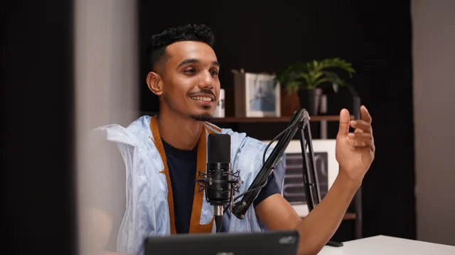 Smiling young man recording a podcast in a cozy home studio with professional microphone setup. Check the data behind each podcast SEO channel