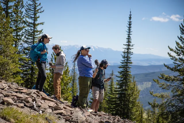 A group of people stand in the mountains with some trees around. Two of them hold microphones. Podcast SEO data protection: consent and privacy