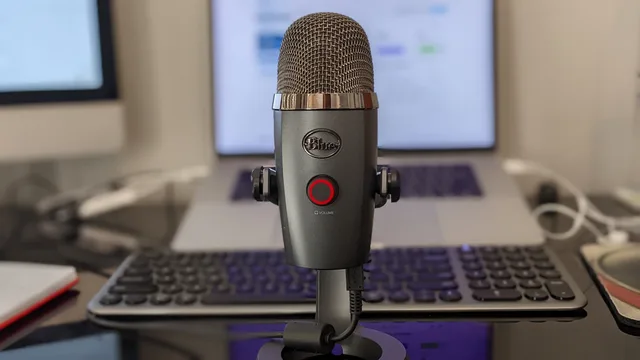 Close-up of a microphone with a blurred keyboard and laptop in a home office setup. Ideal for podcasting content. Seven data sources behind the podcast SEO market outlook