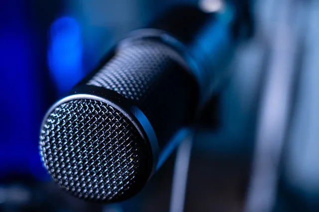 Detailed close-up of a professional studio microphone with a blurred blue background. How to find citable sources for podcast SEO UK regulations